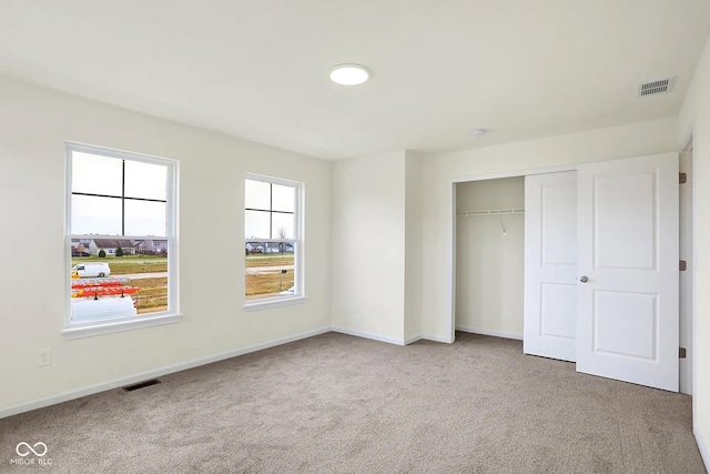 unfurnished bedroom with carpet, a closet, visible vents, and baseboards