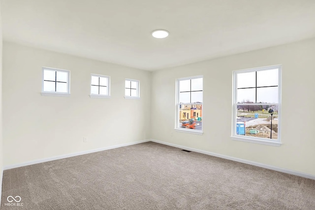 carpeted spare room with visible vents and baseboards