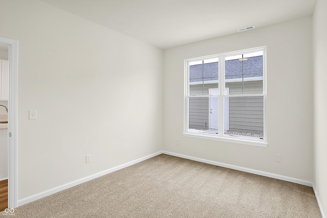 spare room featuring carpet floors, visible vents, and baseboards