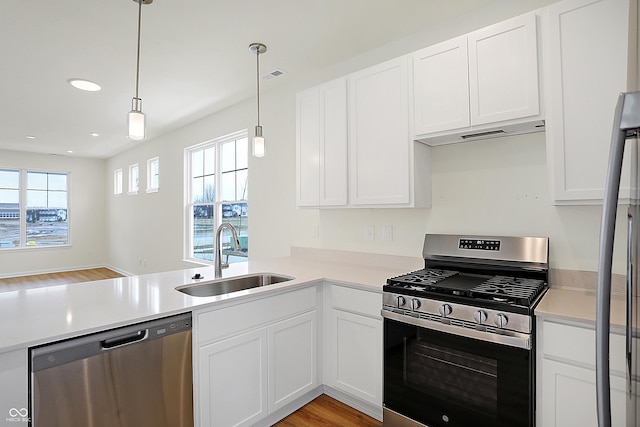 kitchen featuring light countertops, visible vents, appliances with stainless steel finishes, a sink, and under cabinet range hood