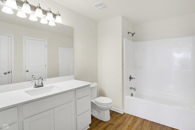 bathroom featuring toilet, wood finished floors, visible vents, vanity, and  shower combination