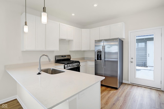 kitchen featuring stainless steel appliances, light countertops, a sink, and a peninsula