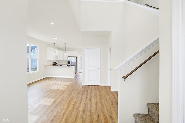 unfurnished living room with light wood-style flooring, stairs, baseboards, and recessed lighting