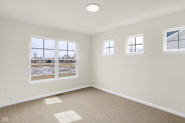 carpeted spare room featuring visible vents and baseboards