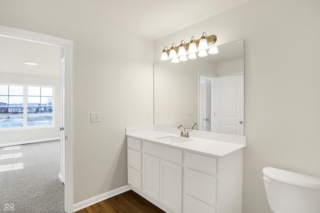 half bath featuring toilet, vanity, and baseboards