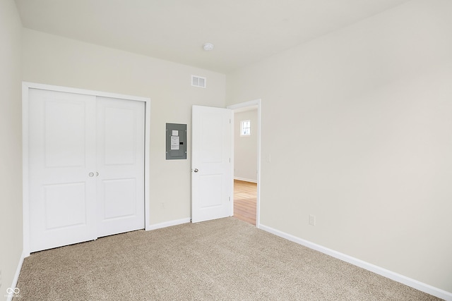 unfurnished bedroom featuring carpet flooring, visible vents, baseboards, a closet, and electric panel