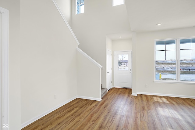 entrance foyer with baseboards, a towering ceiling, wood finished floors, stairs, and recessed lighting