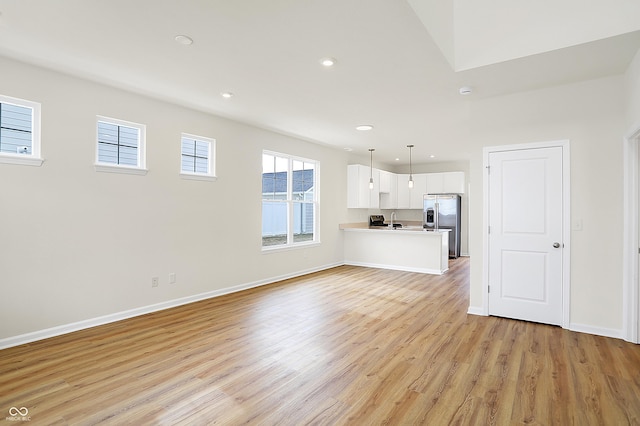 unfurnished living room featuring recessed lighting, a sink, light wood-style flooring, and baseboards