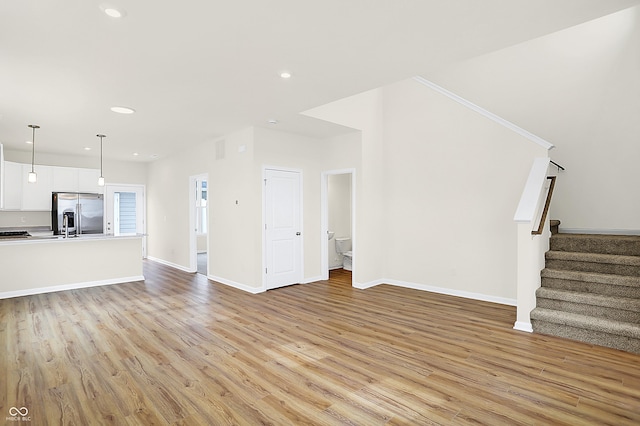 unfurnished living room with stairs, recessed lighting, light wood-type flooring, and baseboards