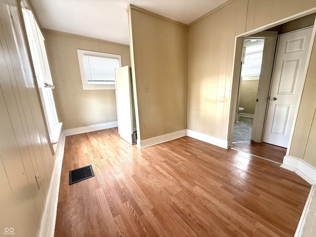 interior space featuring visible vents, wood walls, baseboards, and wood finished floors