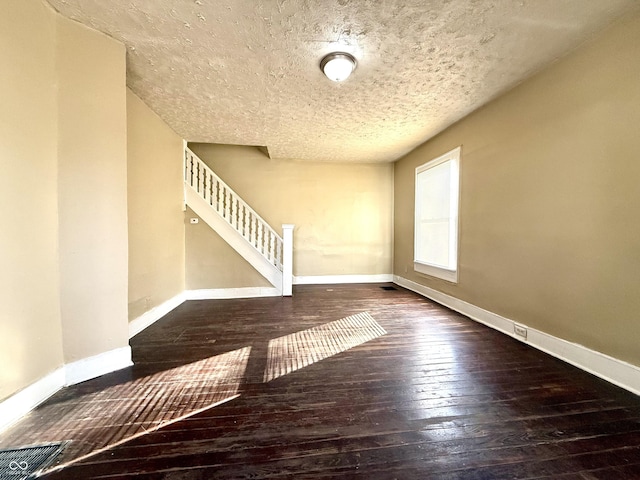 interior space with wood-type flooring, stairs, baseboards, and a textured ceiling