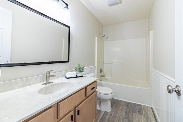 bathroom featuring toilet, a wainscoted wall, wood finished floors, a textured ceiling, and vanity