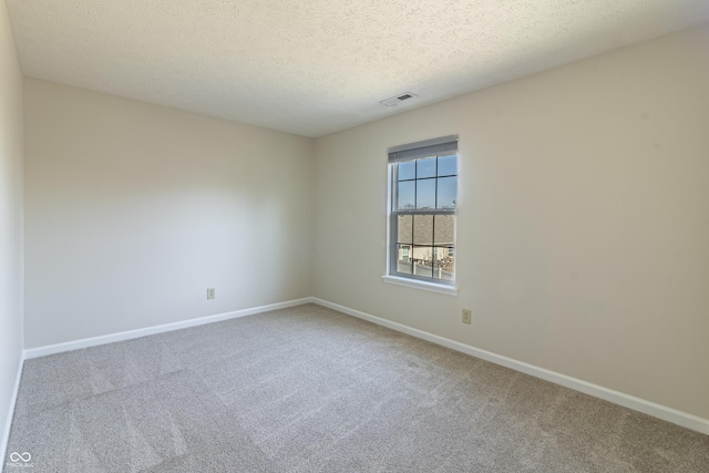 unfurnished room with a textured ceiling, carpet floors, visible vents, and baseboards