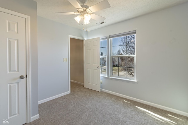 unfurnished bedroom with a textured ceiling, carpet floors, visible vents, and baseboards