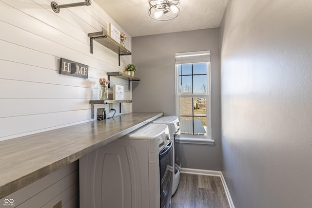 washroom with dark wood finished floors, washing machine and dryer, a textured ceiling, laundry area, and baseboards