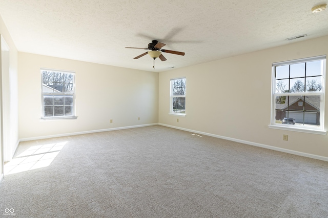 empty room featuring carpet, visible vents, a ceiling fan, a textured ceiling, and baseboards