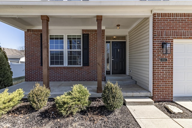 entrance to property featuring a garage and brick siding