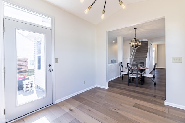 dining room featuring a chandelier, vaulted ceiling, baseboards, and wood finished floors