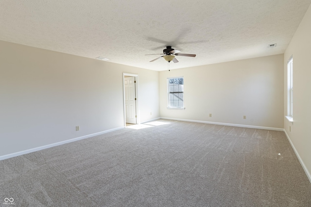 empty room featuring visible vents, a ceiling fan, light carpet, a textured ceiling, and baseboards