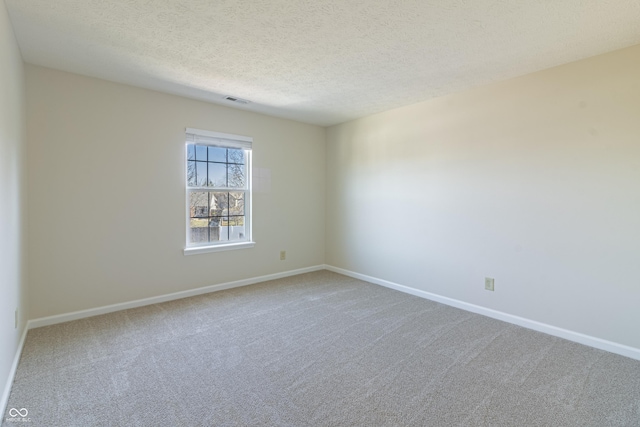 carpeted spare room with visible vents, baseboards, and a textured ceiling