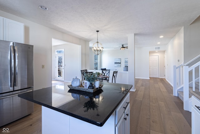 kitchen featuring dark wood-style floors, freestanding refrigerator, white cabinetry, and dark countertops