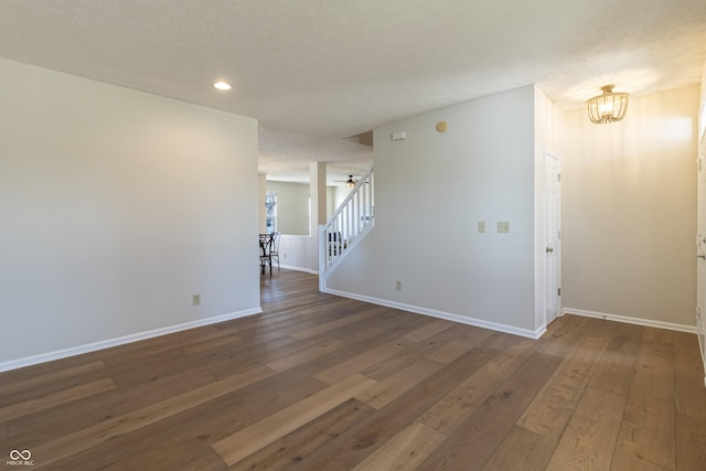 spare room with a notable chandelier, stairway, hardwood / wood-style flooring, and baseboards