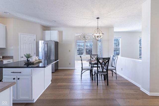 dining area featuring a chandelier, a textured ceiling, wood finished floors, and baseboards