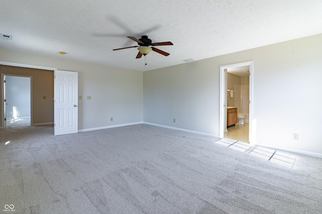 spare room featuring baseboards, light colored carpet, visible vents, and a textured ceiling