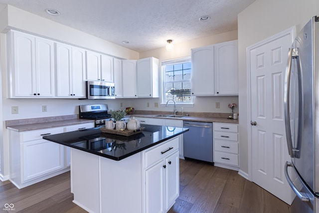 kitchen featuring stainless steel appliances, dark wood finished floors, white cabinetry, and a sink