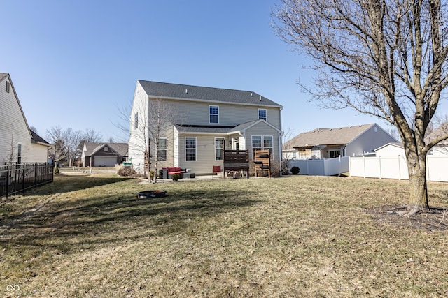 back of property with a fenced backyard, a lawn, and a wooden deck