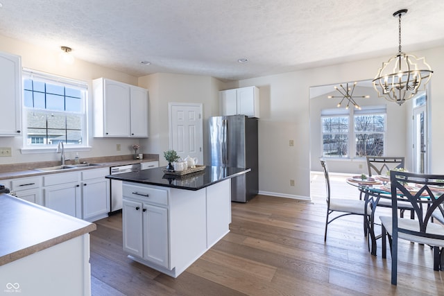 kitchen with appliances with stainless steel finishes, plenty of natural light, dark wood-type flooring, and a sink