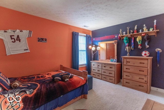 carpeted bedroom with visible vents, a textured ceiling, and baseboards