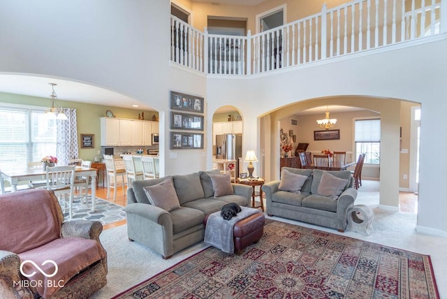 living room with arched walkways, a high ceiling, baseboards, and an inviting chandelier