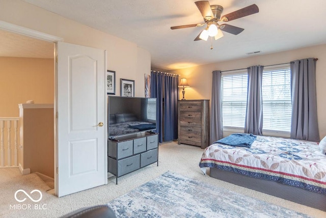 carpeted bedroom featuring a ceiling fan and visible vents