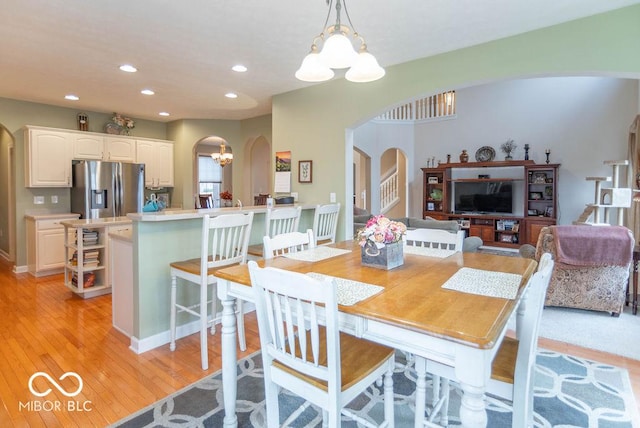 dining room featuring light wood-style floors, stairway, arched walkways, and recessed lighting