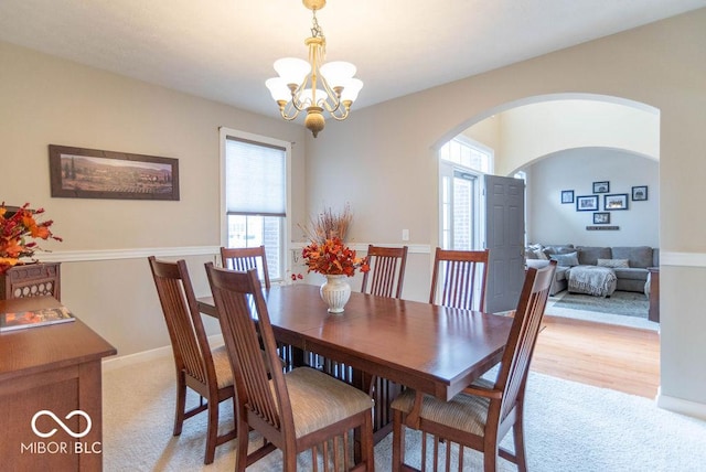 dining room with baseboards, arched walkways, and a notable chandelier