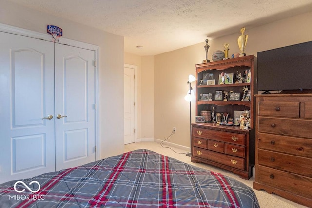 carpeted bedroom featuring a closet, baseboards, and a textured ceiling