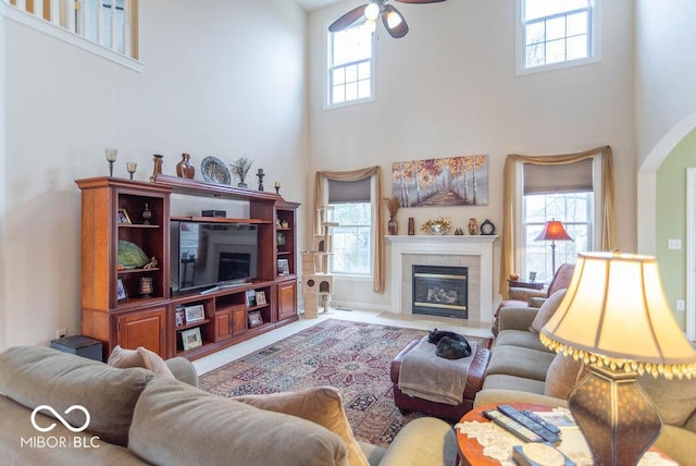 living area with plenty of natural light, a towering ceiling, and a tiled fireplace