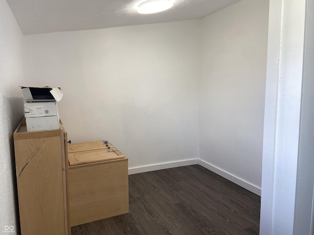 unfurnished room featuring dark wood-style flooring and baseboards