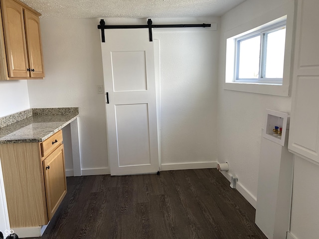 washroom featuring a textured ceiling, dark wood-style flooring, washer hookup, and cabinet space