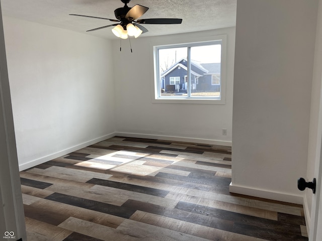 empty room featuring a ceiling fan, a textured ceiling, baseboards, and wood finished floors