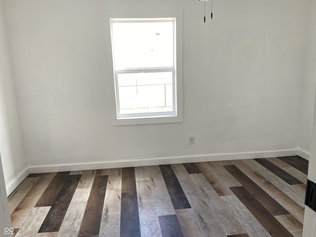 spare room with baseboards and wood finished floors