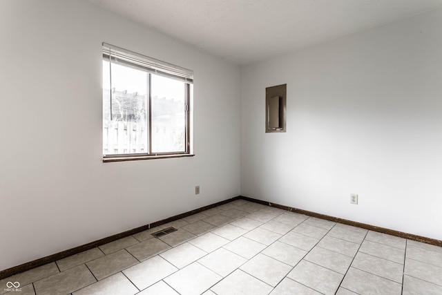 spare room featuring light tile patterned floors, visible vents, and baseboards