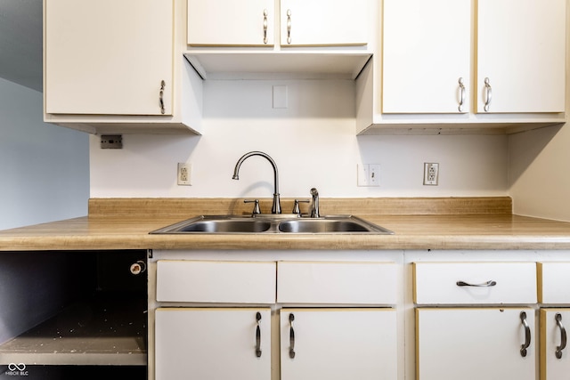 kitchen featuring white cabinets, light countertops, and a sink