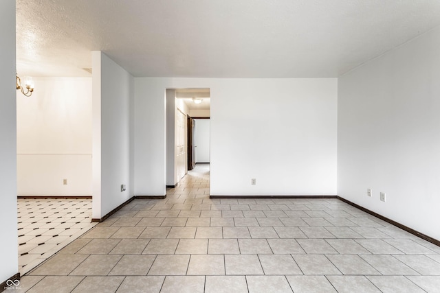 empty room featuring a chandelier, baseboards, and tile patterned floors