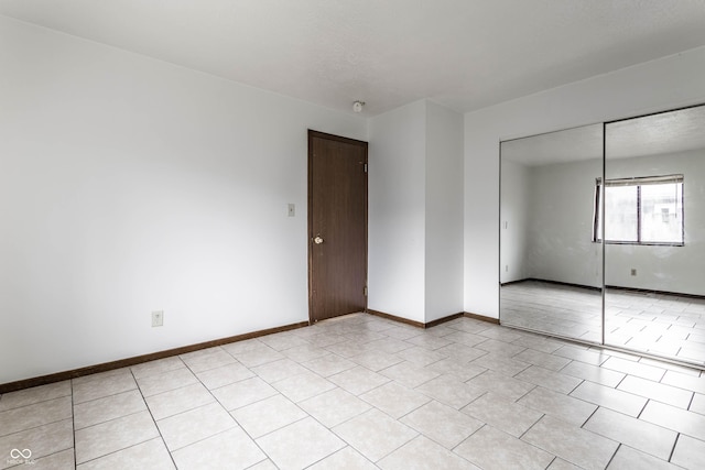 empty room with light tile patterned floors and baseboards