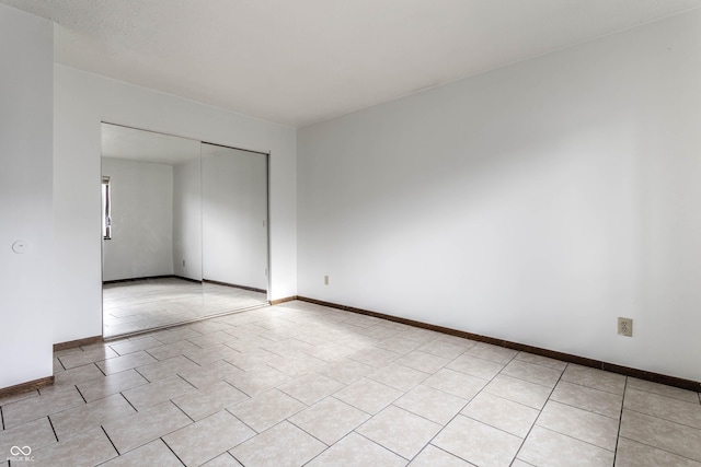 spare room with light tile patterned floors and baseboards