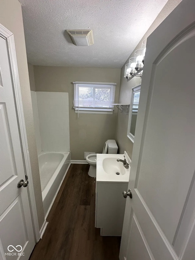 bathroom featuring visible vents, toilet, a textured ceiling, vanity, and wood finished floors