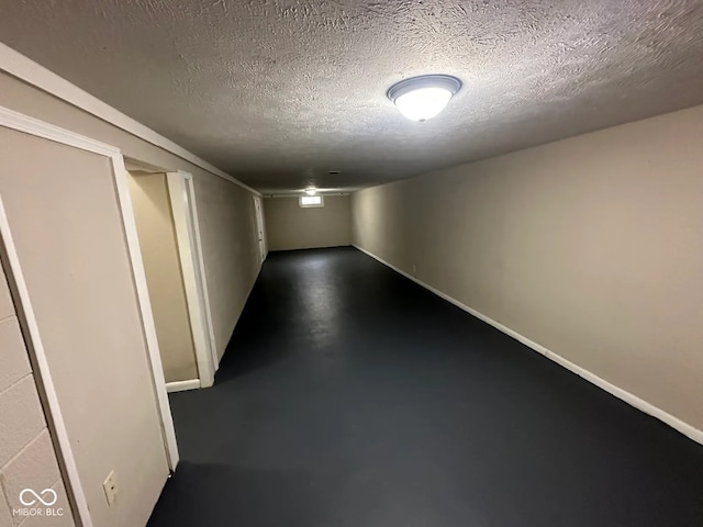 empty room featuring finished concrete flooring, a textured ceiling, and baseboards