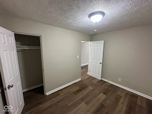 unfurnished bedroom with a closet, a textured ceiling, baseboards, and wood finished floors